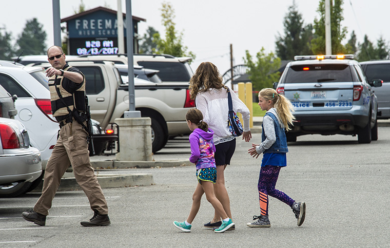 A law enforcement officer leads a family away from Freeman High School after a shooting, September 13, 2017. (Photo by Dan Pelle/The Spokesman-Review)